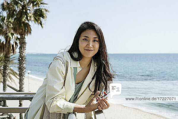 Beautiful female tourist leaning on railing by beach