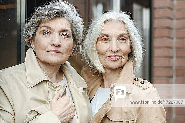 Mature female friends wearing trench coats