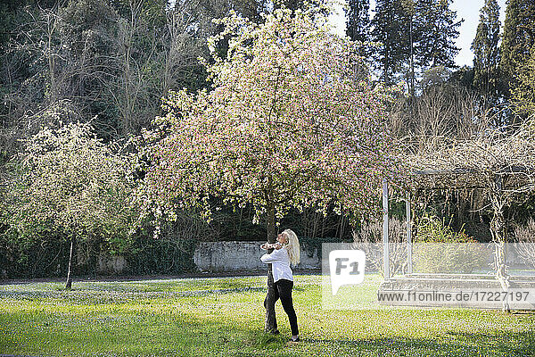 Caucasian woman embracing tree trunk during springtime