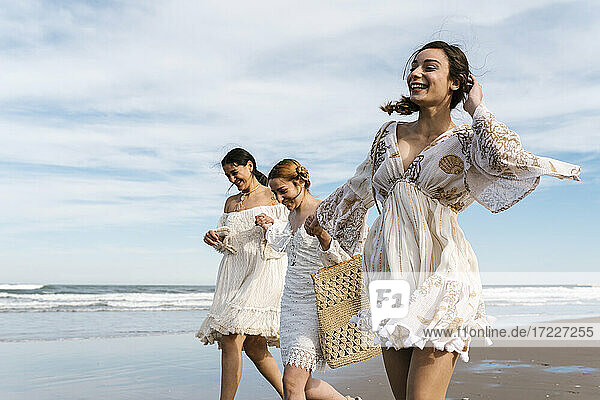 Female friends holding hands while walking at beach