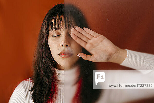 Woman with eyes closed touching plastic sheet