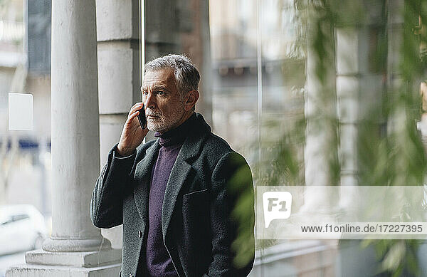 Modischer Mann  der auf dem Hotelflur mit einem Mobiltelefon spricht