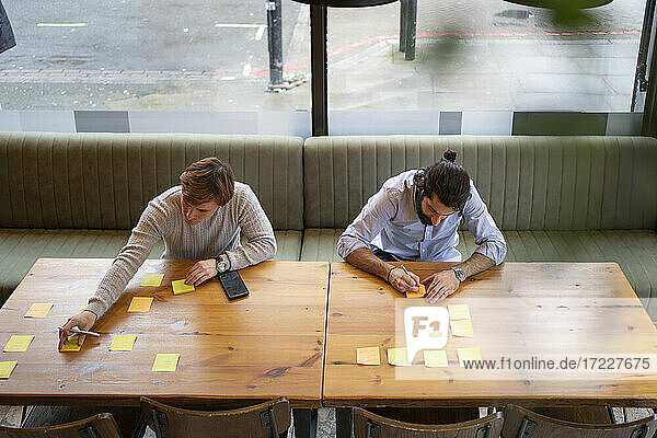 Male coworkers brainstorming using adhesive note while working in office