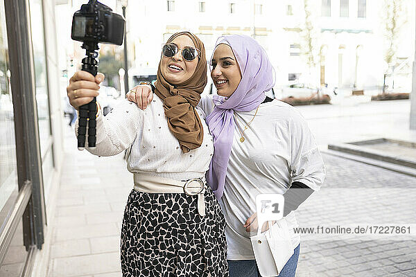 Freundinnen in Hijabs  die mit einer Digitalkamera in der Stadt vloggen