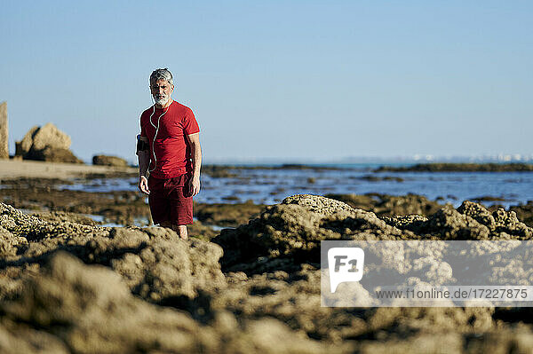 Mann steht auf Felsen am Strand