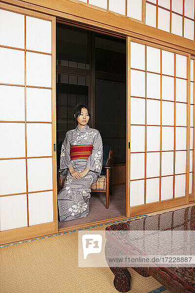 Gelassene junge Japanerin im Kimono an der Shoji-Tür
