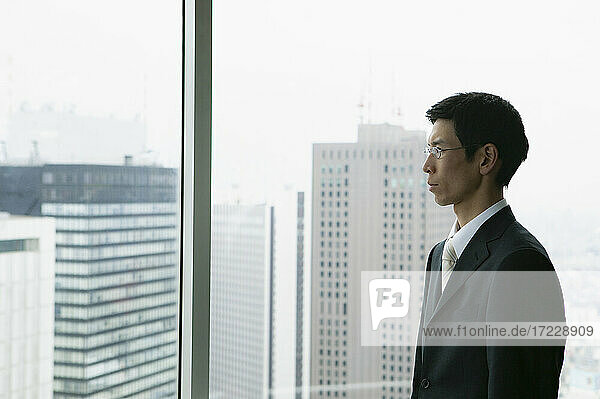 Geschäftsmann schaut aus städtischen Hochhaus Büro Fenster