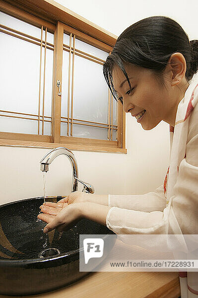 Junge Frau beim Händewaschen am Waschbecken im Spa