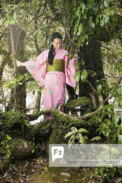 Junge Frau in rosa Kimono unter schönen Bäumen