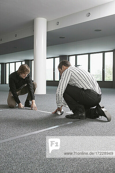 Geschäftsleute messen und markieren den Boden im neuen Büro