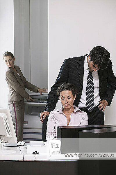 Geschäftsmann schaut über die Schulter einer Geschäftsfrau im Büro