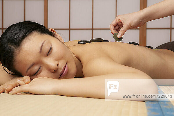 Ruhige junge Frau erhält Hot-Stone-Massage im Spa