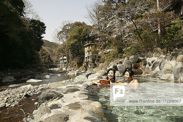 Glückliche junge Frauen  die im sonnigen Onsen-Pool eintauchen  Izu  Japan