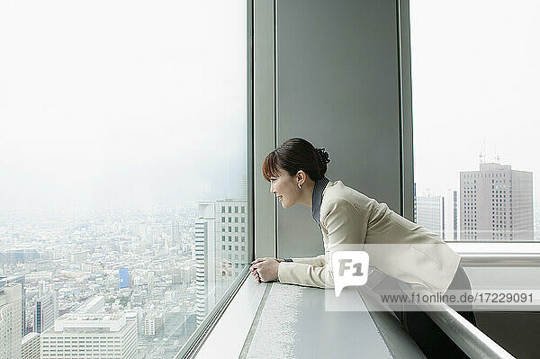 Geschäftsfrau mit Blick auf die Stadt aus dem Hochhaus Büro
