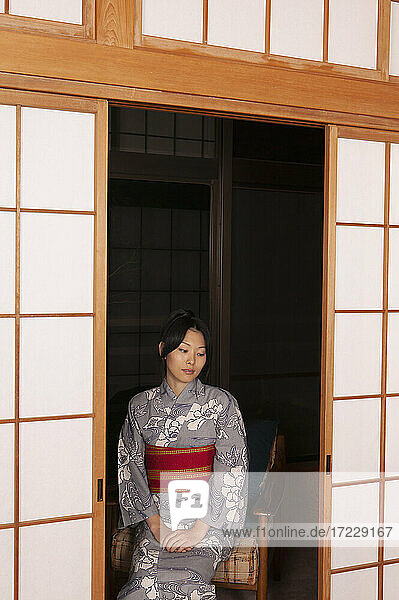 Schöne heitere junge Frau im Kimono an Shoji-Bildschirm Türen