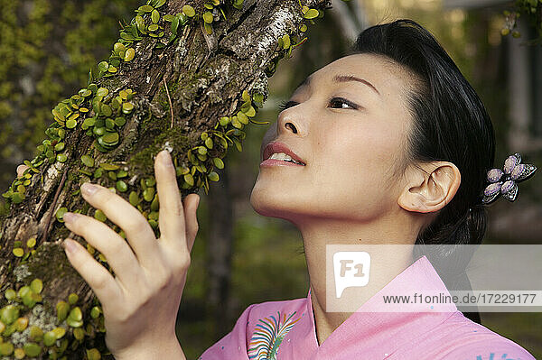 Schöne junge Frau schaut auf Knospen wachsen auf Baum