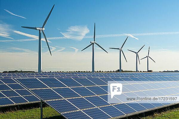 Windturbinen-Energieerzeuger in einem Windpark  mit darunter liegenden Solarzellen.