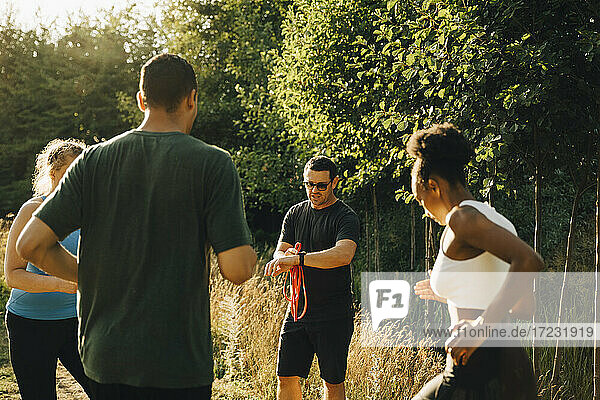 Fitness-Instruktor trainiert männliche und weibliche Athleten beim Training im Park