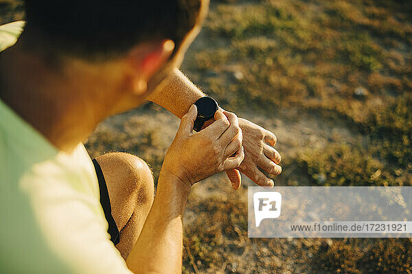 Ausgeschnittenes Bild eines Sportlers  der die Zeit auf seiner Armbanduhr überprüft