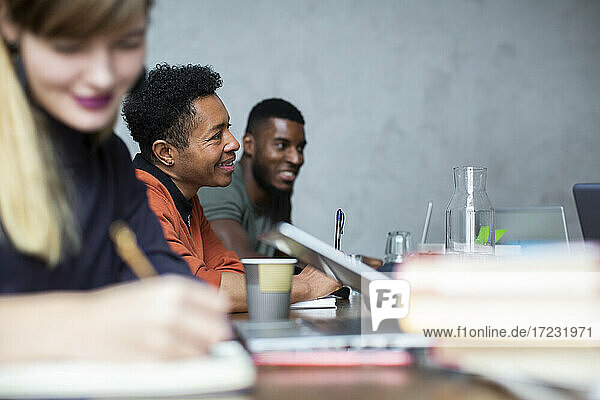 Lächelnde männliche und weibliche Kollegen in der Diskussion während der Sitzung im kreativen Büro