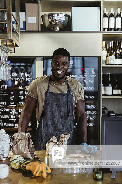 Portrait of smiling male entrepreneur standing in delicatessen shop