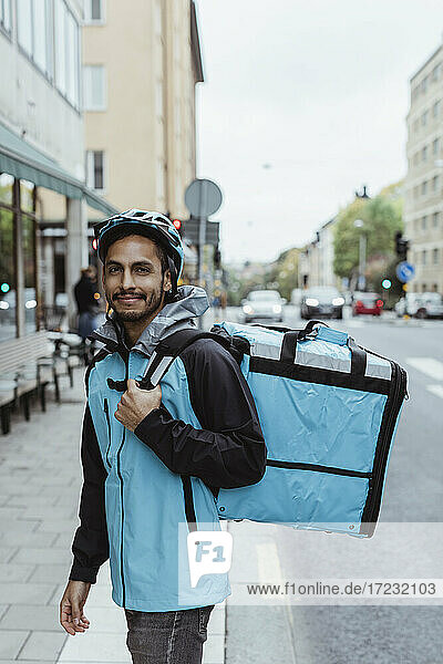 Porträt von lächelnden Lieferung Mann auf dem Bürgersteig in der Stadt