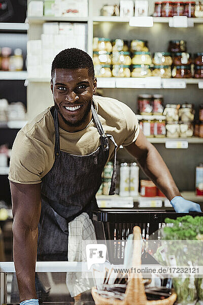 Portrait of smiling male owner with basket in deli store