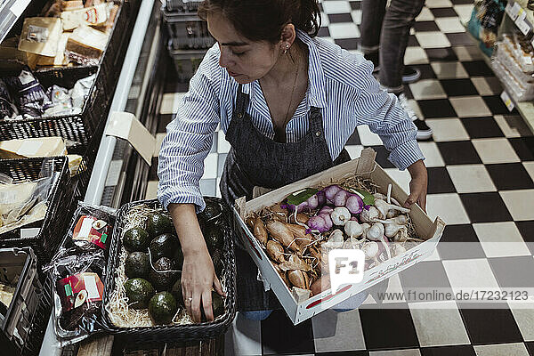 Hohe Winkel Ansicht der Verkäuferin Arrangieren von Obst und Gemüse in der Box auf deli speichern