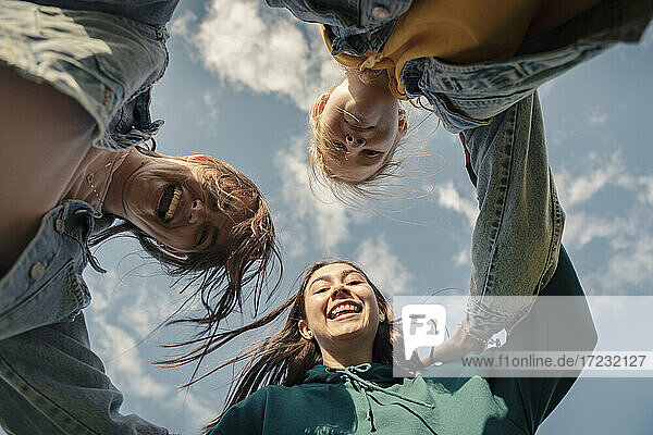 Lächelnde Freundinnen schauen gegen den Himmel an einem sonnigen Tag