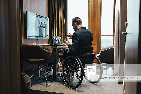 Behinderter Geschäftsmann mit Kollegen per Videokonferenz im Büro während einer Pandemie