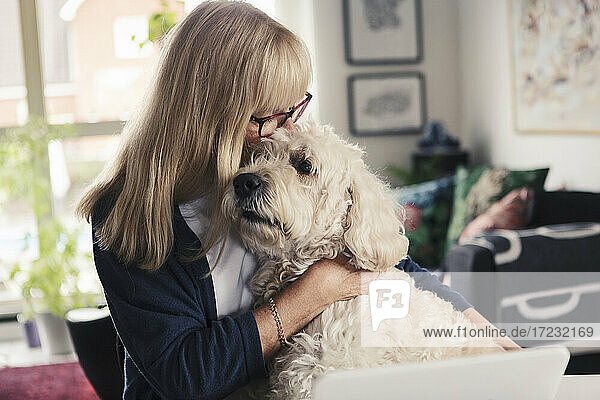 Blonde Frau küssen und umarmen Hund zu Hause