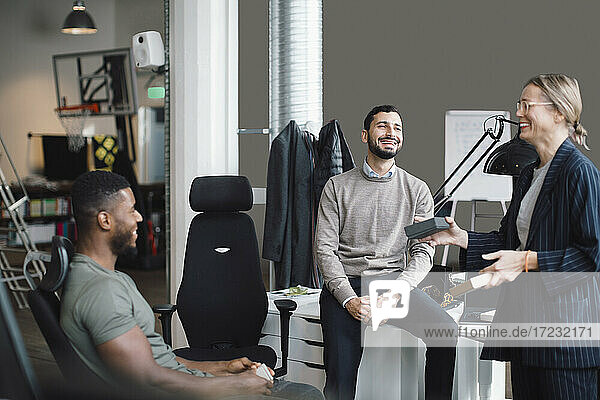 Female and male colleagues laughing while discussing over product at creative office