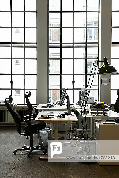 Interieur eines kreativen Büros mit Schreibtischen und Lampe