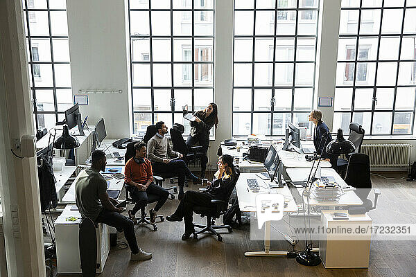 High angle view of male and female professionals discussing during meeting in creative office