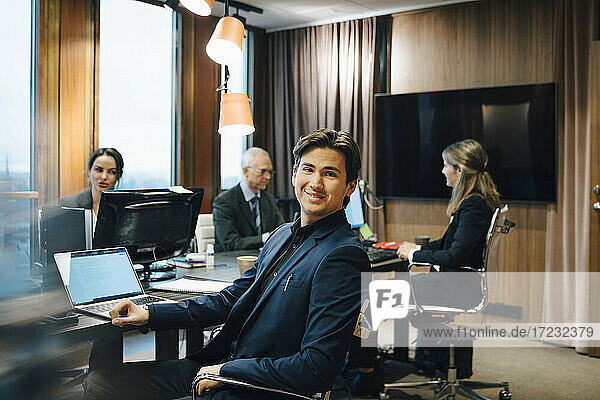 Portrait of male entrepreneur with colleagues sitting in board room