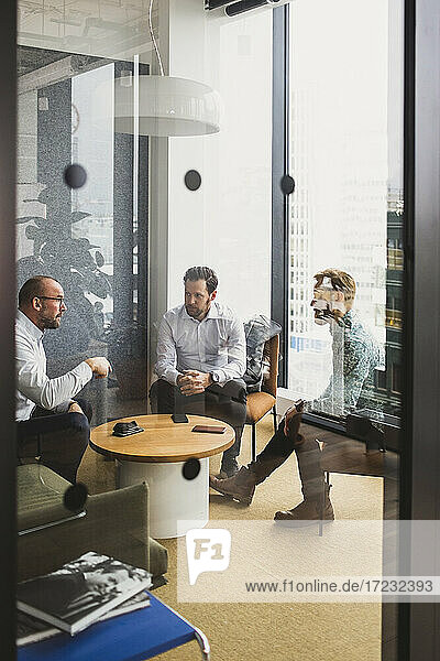Business people seen through door while discussing with each other at office