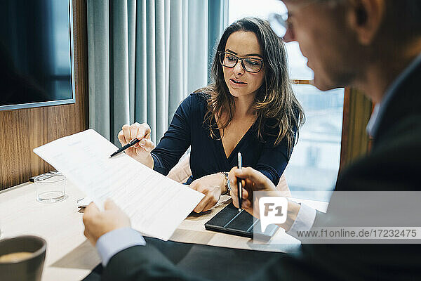Männlicher und weiblicher Unternehmer beim Brainstorming über einem Dokument während einer Besprechung im Büro