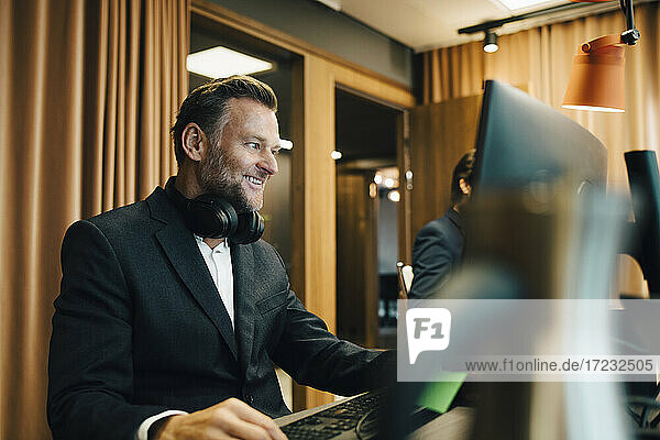 Lächelnde männliche Unternehmer arbeiten am Computer im Büro