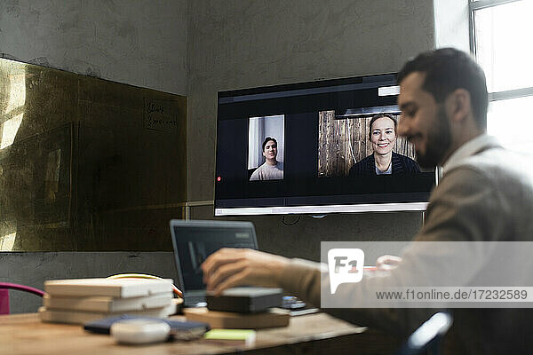 Male entrepreneur in video conference with customers in office