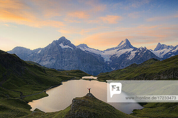 Fröhlicher Wanderer mit Blick auf Wetterhorn  Schreckhorn und Finsteraarhorn vom Bachalpsee in der Morgendämmerung  Berner Oberland  Schweiz  Europa