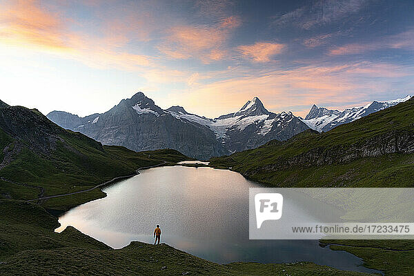 Wanderer bewundert den Sonnenaufgang vom Ufer des Bachalpsees  Grindelwald  Berner Oberland  Kanton Bern  Schweiz  Europa