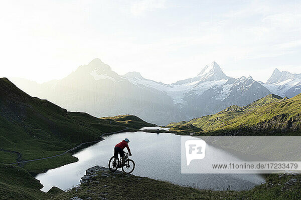 Mountainbiker fahren bergab am Bachalpsee in der Morgendämmerung  Grindelwald  Berner Oberland  Kanton Bern  Schweiz  Europa