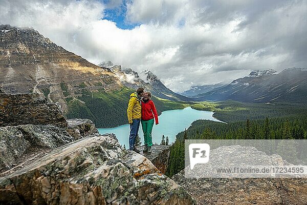 Paar küsst sich  Ausblick auf türkisfarbenen Gletschersee umgeben von Wald  Peyto Lake  Rocky Mountains  Banff-Nationalpark  Provinz Alberta  Kanada  Nordamerika