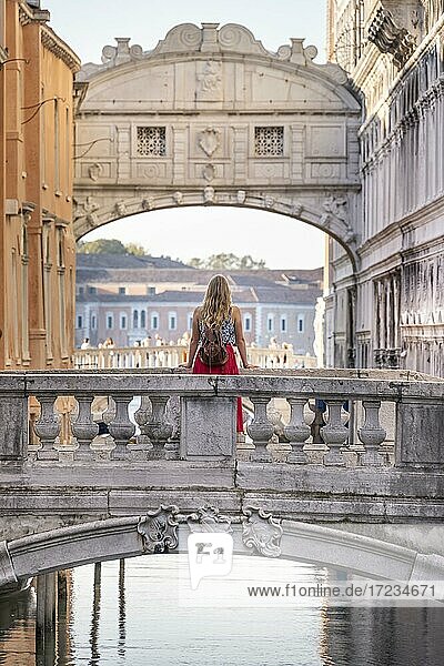 Junge Frau mit rotem Rock  Touristin lehnt an Brückengeländer  Brücke über dem Rio di Palazzo  hinten Seufzerbrücke  Venedig  Venetien  Italien  Europa