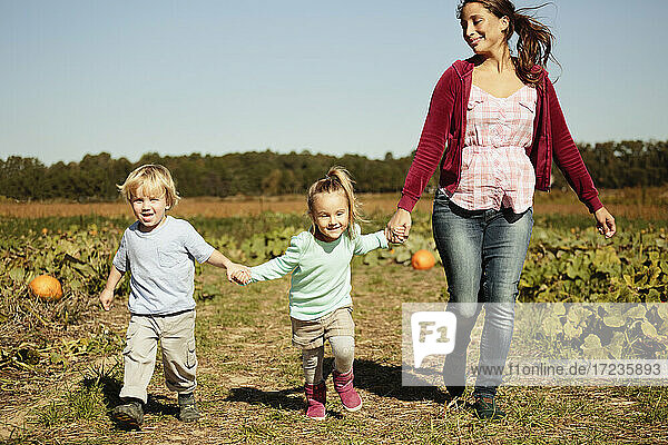 Mother with two children running in pumpkin field