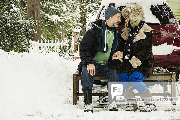 Mature couple sitting on toboggan in snow