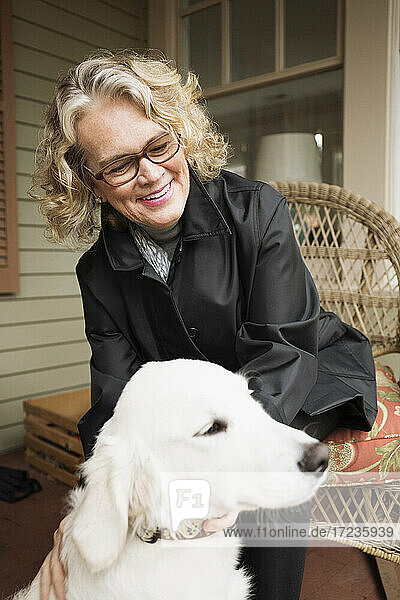 Ältere Frau sitzt auf Veranda mit Hund