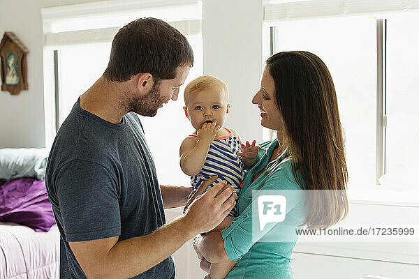 Portrait of mid adult couple with baby daughter in bedroom