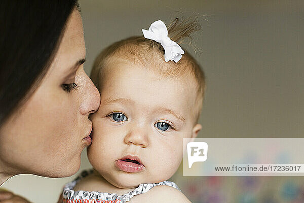 Close up of mid adult mother kissing baby daughter on cheek