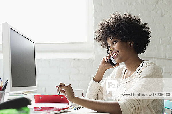Junge Frau am Smartphone am Schreibtisch